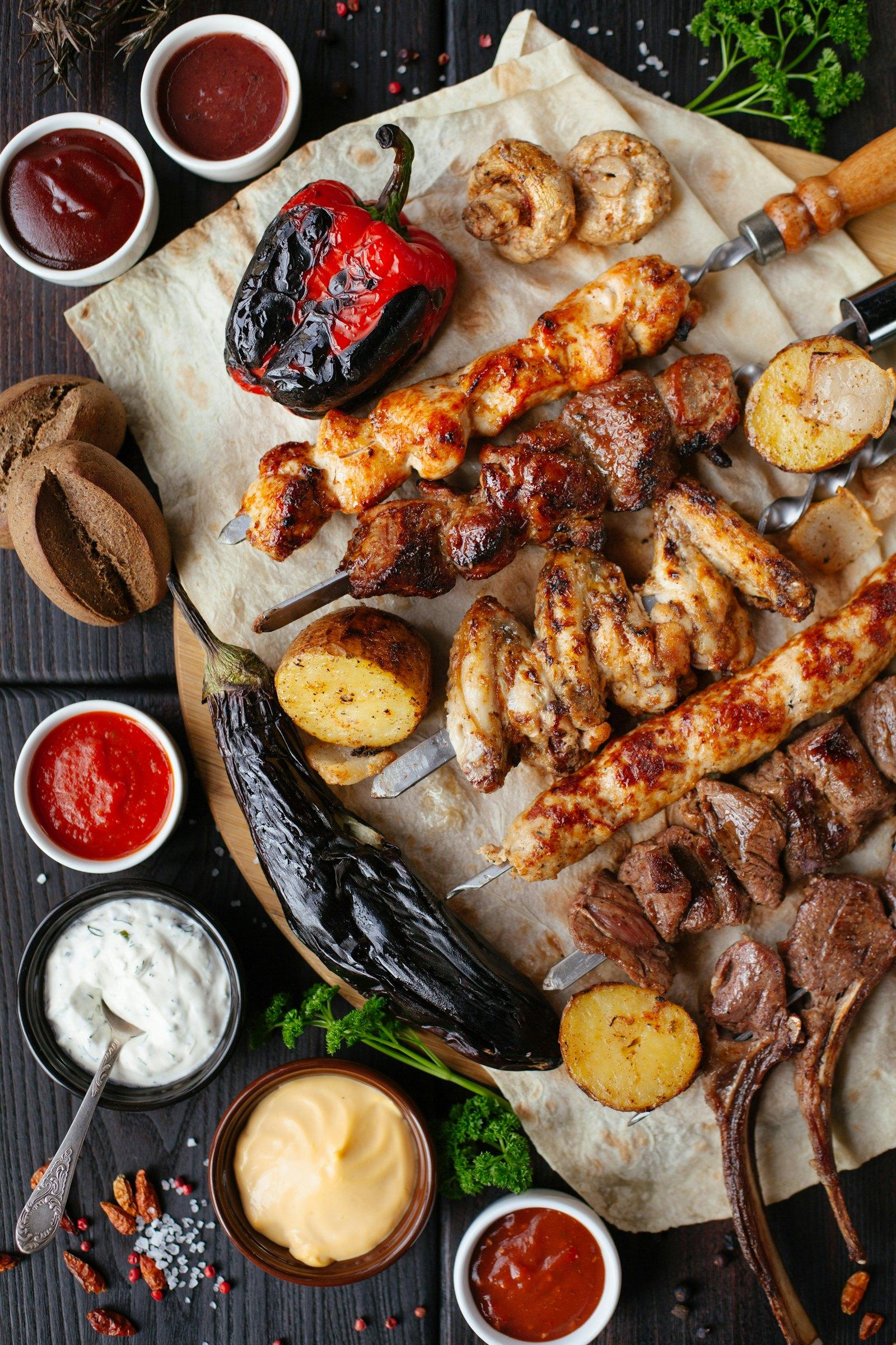 Skewers of fire-grilled meat with sides spread across a table